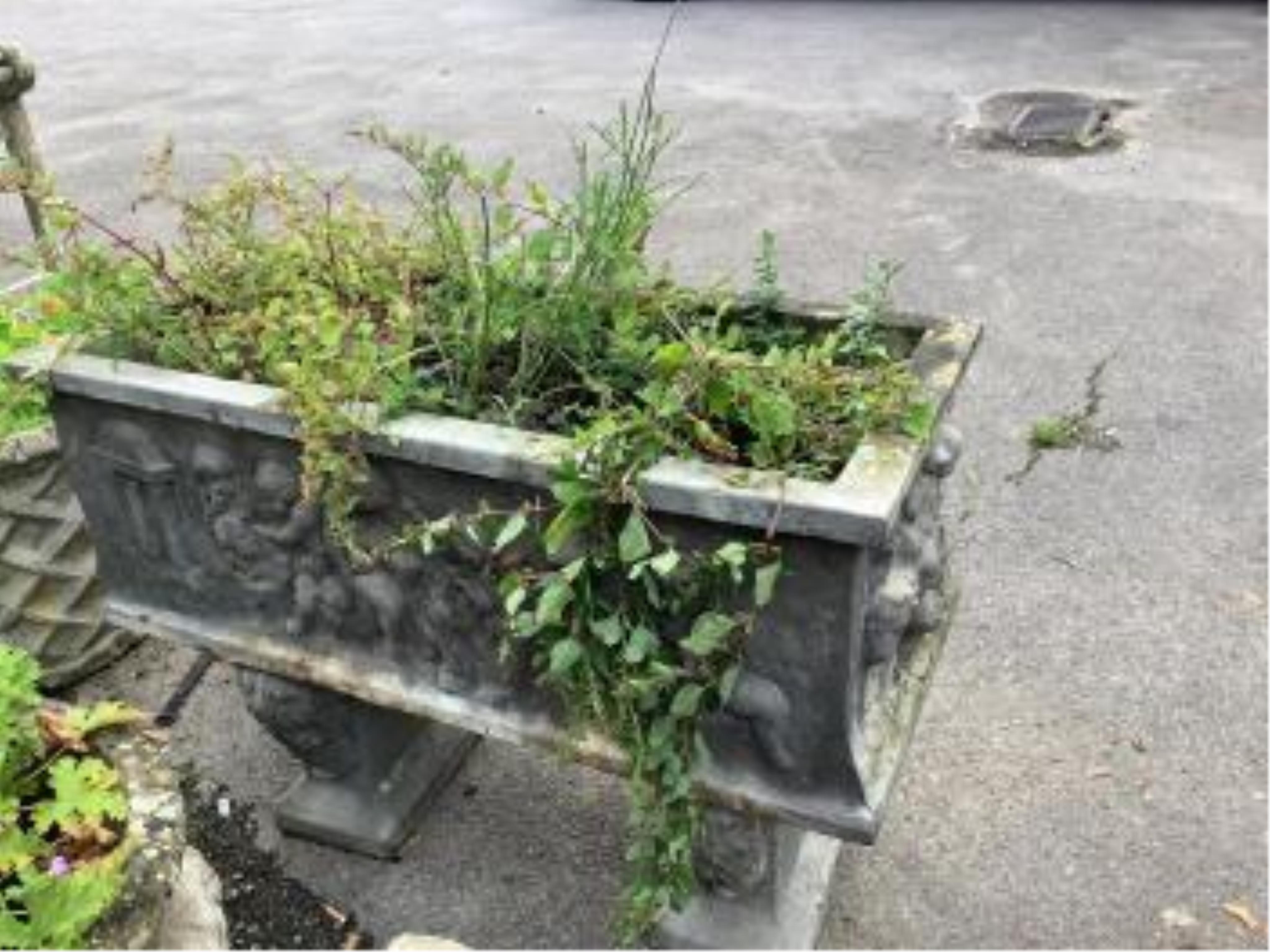 A reconstituted stone rectangular garden trough, moulded with putti, on Roman end plinths, width 89cm, depth 39cm, height 64cm. Condition - fair